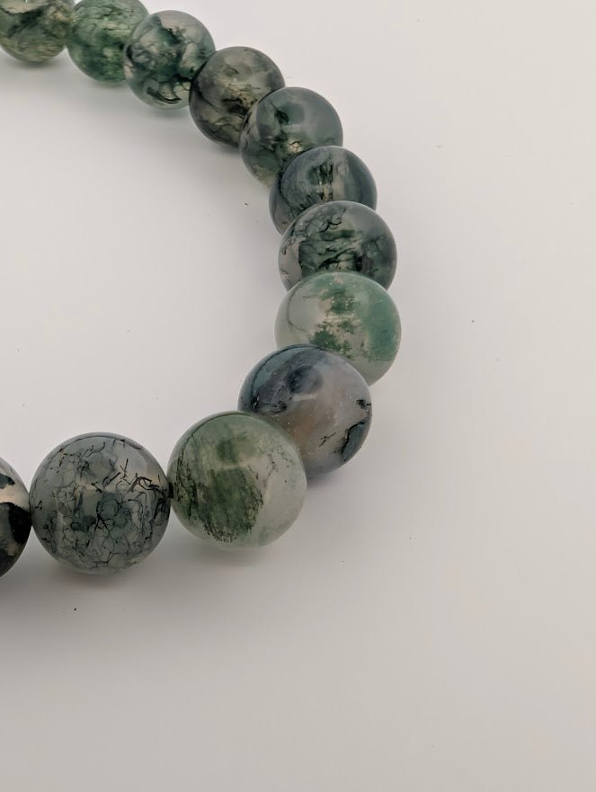 Macro detail of translucent Moss Agate beads with natural patterns.