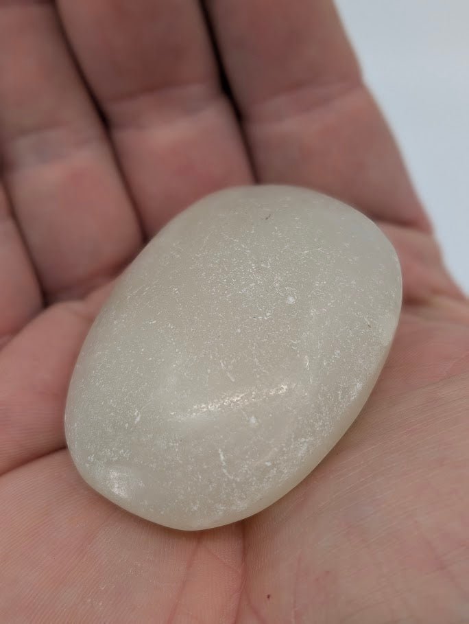 Afghan Jade palm stone in hand showing natural off-white tone and semi-translucent polish