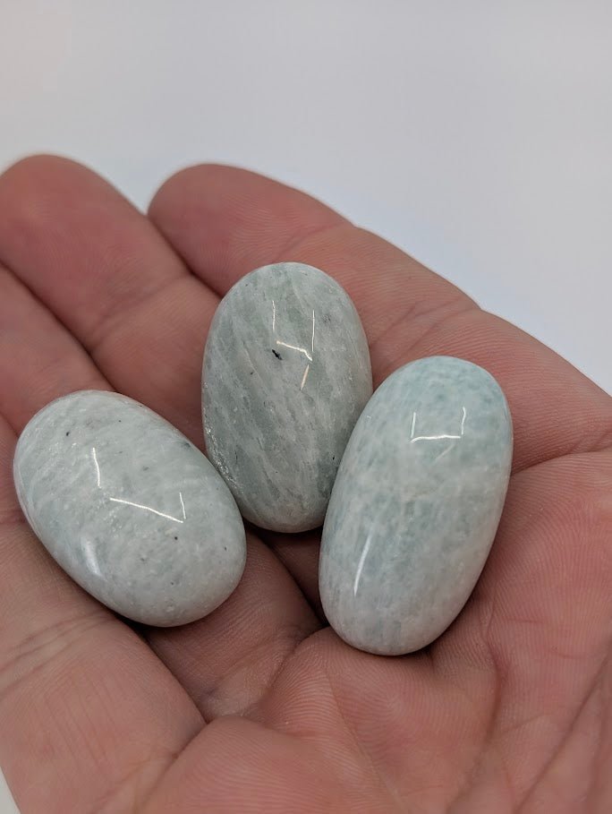 Amazonite tumbled stones shown in hand for scale