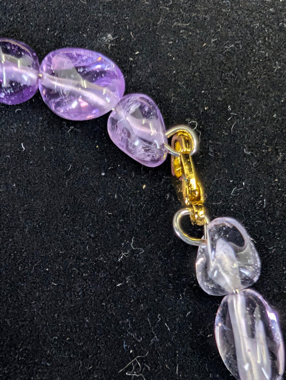 Detail shot of the gold-toned lobster clasp and secure wire loop attachment on a natural Amethyst bead bracelet.