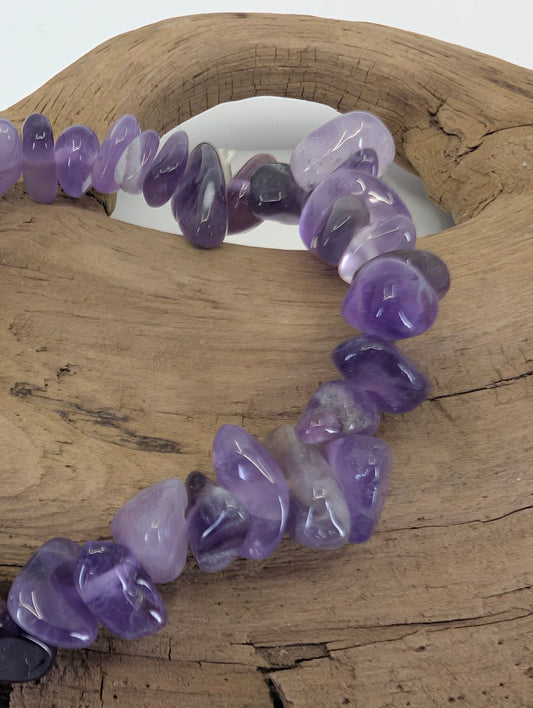 Macro view of Amethyst tumbled chips showing vitreous luster and authentic light-to-dark purple color zones.