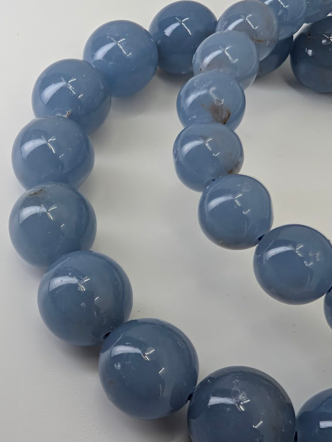 Macro close-up of Angelite bracelet beads showing polished surface and natural inclusions in high quality blue beads
