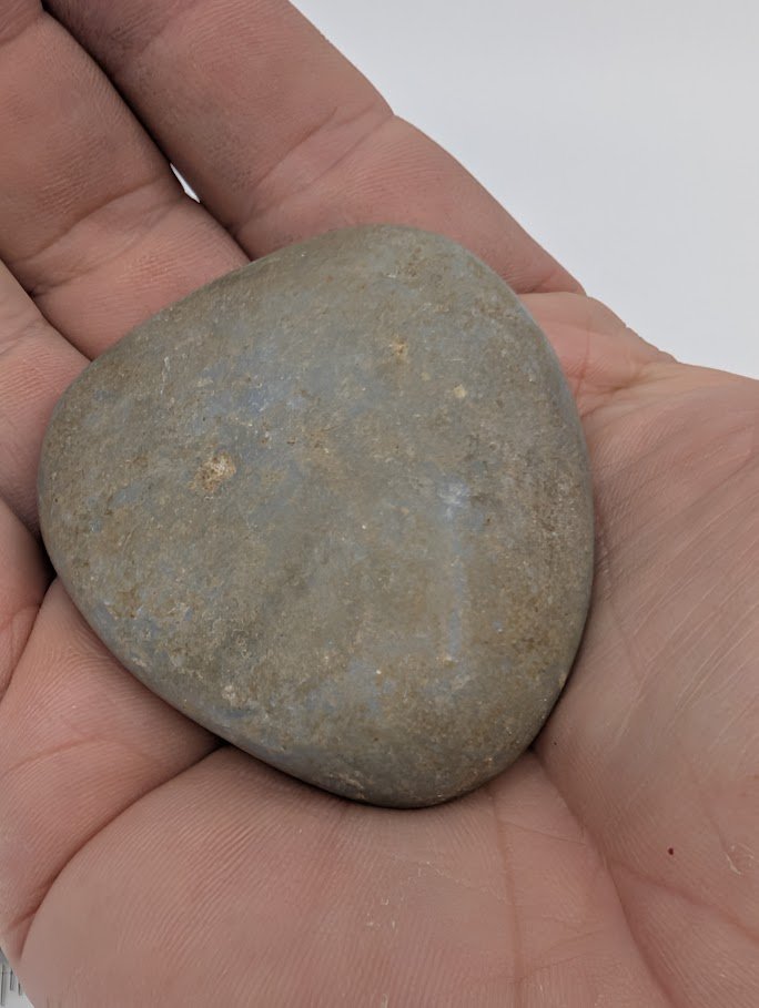 Angelite palm stone in hand showing natural light-blue color and smooth matte polish