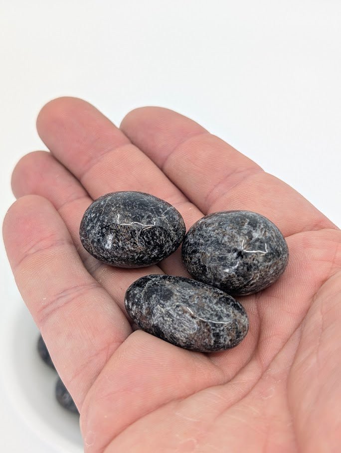 Astrophyllite with Mixed Garnet tumbled stones in hand for size reference