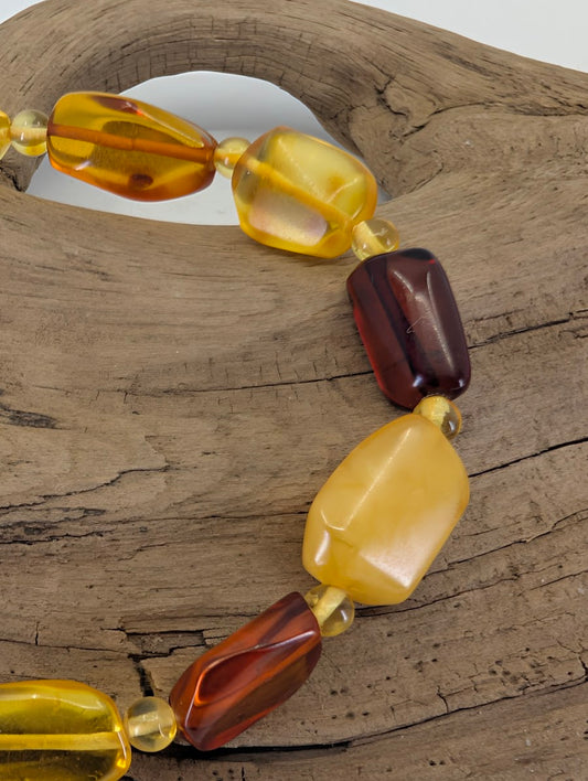 Close-up of 9.5mm freeform amber beads highlighting the contrast between opaque egg-yolk and translucent honey resin.