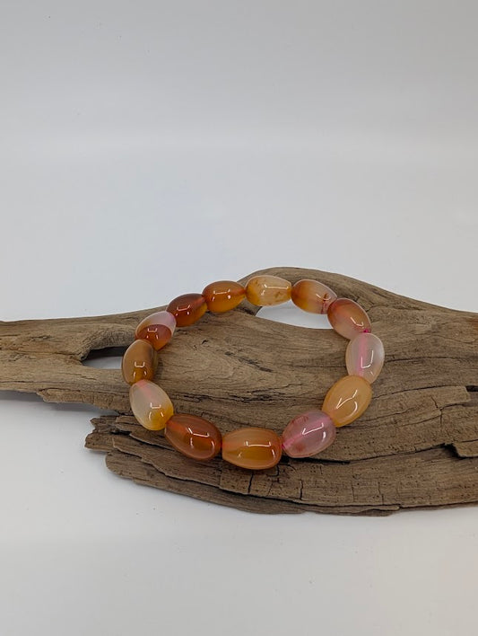 Banded agate bracelet with warm honey and rose tones on driftwood display