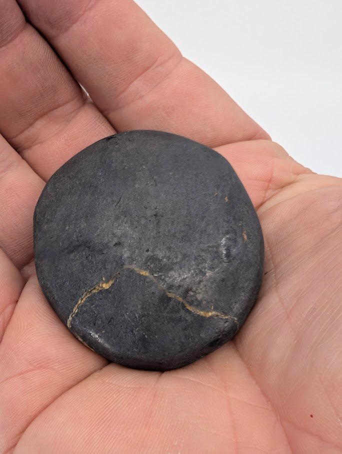 Bitumen palm stone in hand showing natural matte finish and organic shape