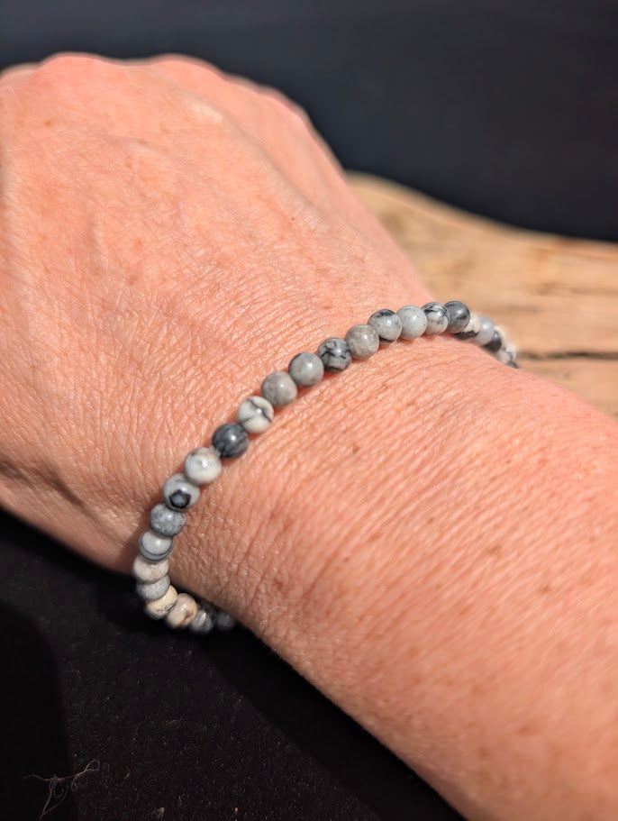 Natural sunlight on a 4mm black and white Black Network Stone stretch bracelet worn on a wrist.