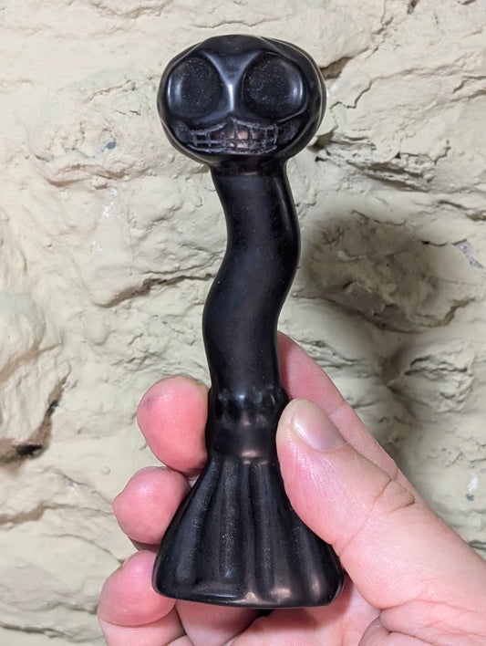 Full-length view of black obsidian skull broom carving