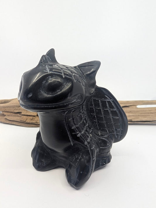 Side profile of a polished Black Obsidian dragon figurine highlighting the vitreous lustre and wing structure.
