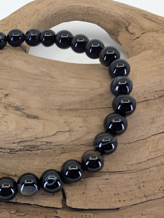 Close-up of 6mm Black Onyx beads highlighting natural grey banding and authentic agate inclusions.