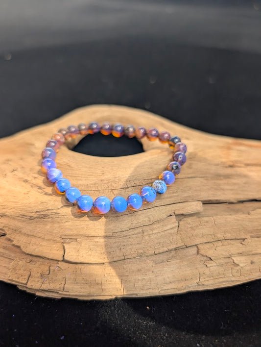 A 6mm Mexican Blue Amber beaded bracelet demonstrating a vivid, natural neon blue fluorescence when exposed to UV light.