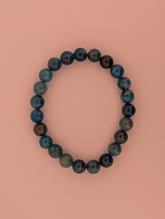 Overhead view of 8mm Blue Apatite bracelet on light background