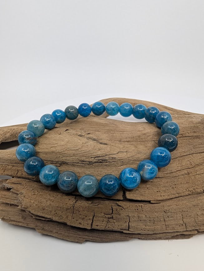 Blue Apatite 8mm round bead stretch bracelet on driftwood showing vivid ocean-blue tones