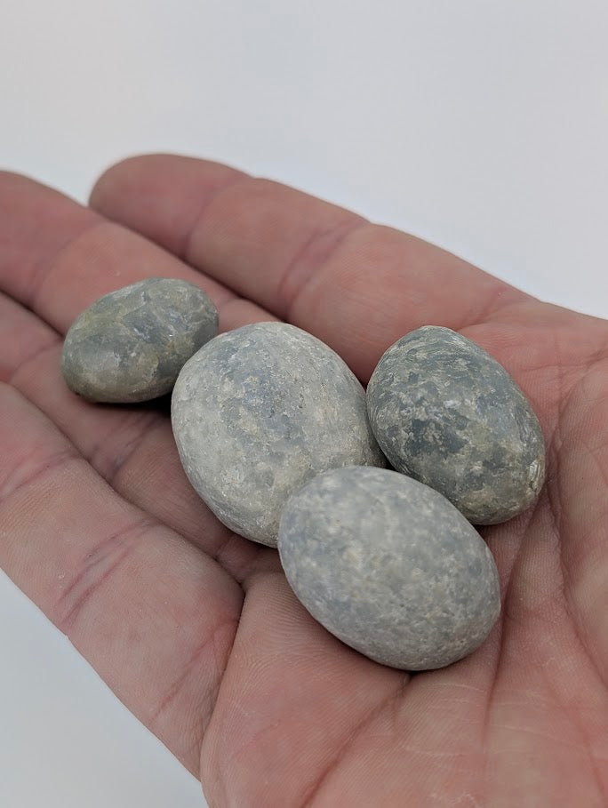 Blue Calcite tumbled stones shown in hand for scale