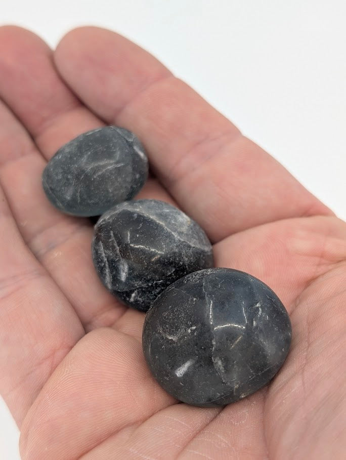 Blue Fluorite tumbled stones in hand for size reference