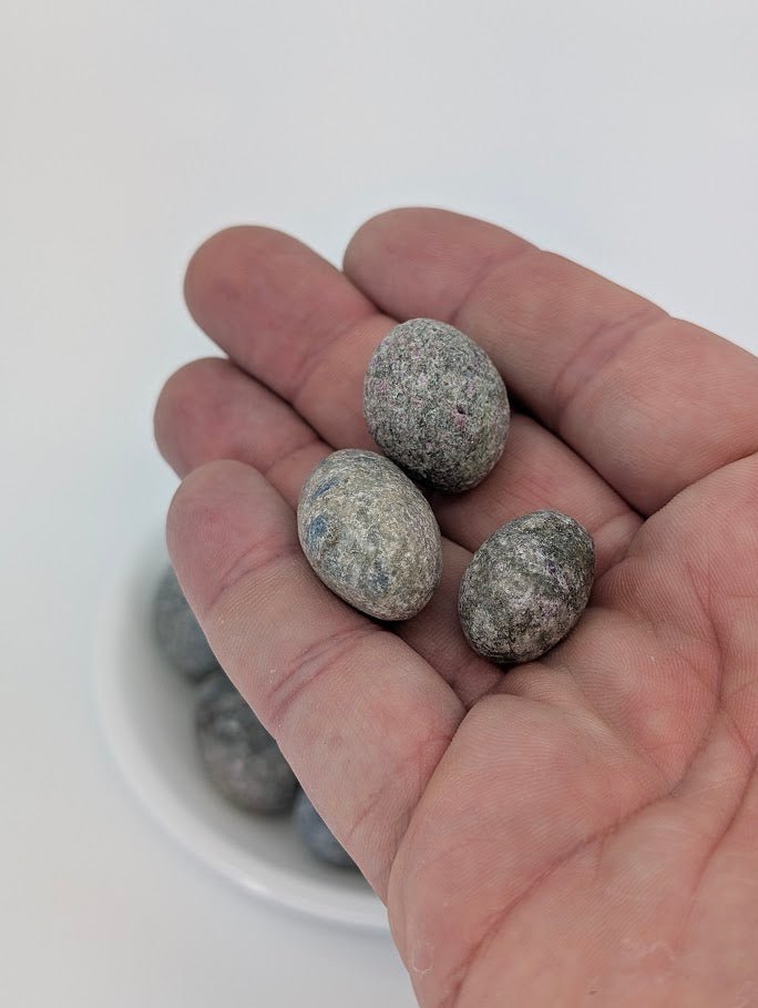 Blue Kyanite tumbled stones shown in hand for size reference