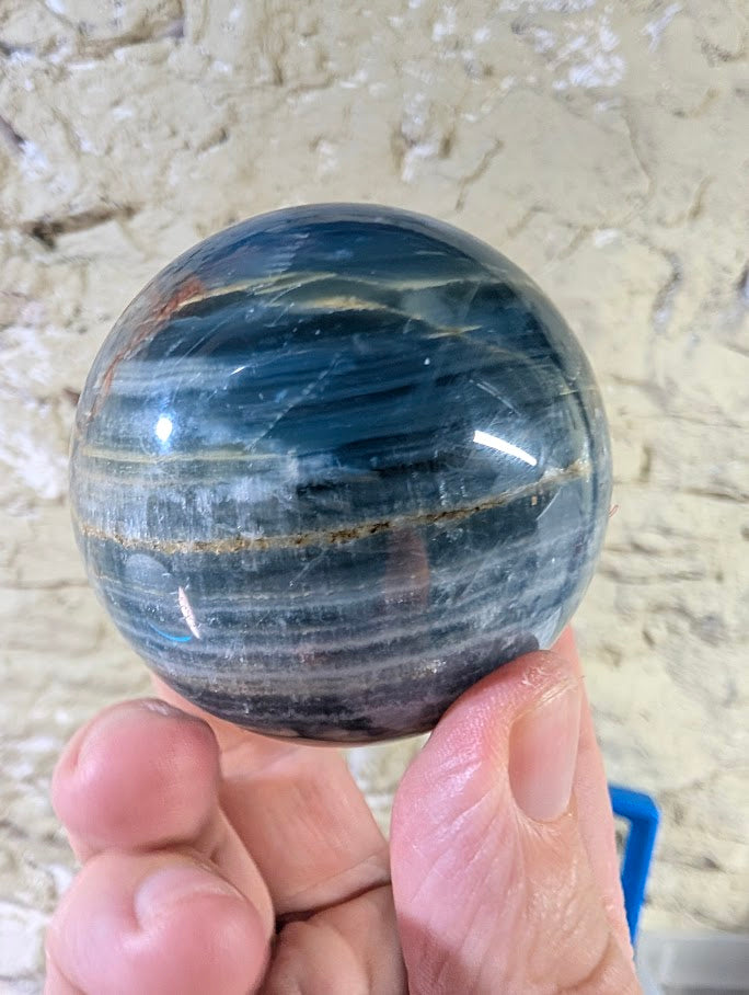 Angled view of blue onyx sphere revealing soft banding and shine