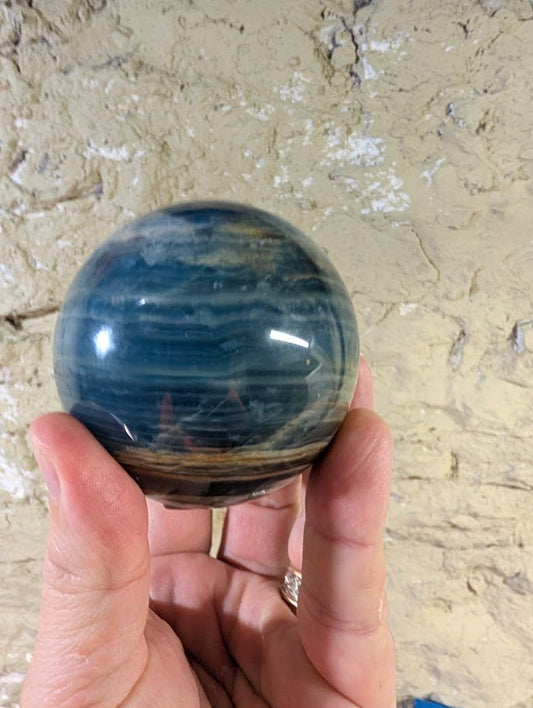 Blue onyx sphere showing subtle layered blue banding from front view