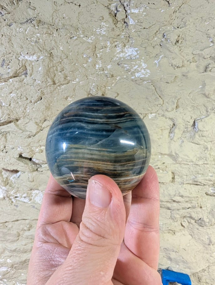 Layered banding in natural calcite sphere with brown and blue zoning