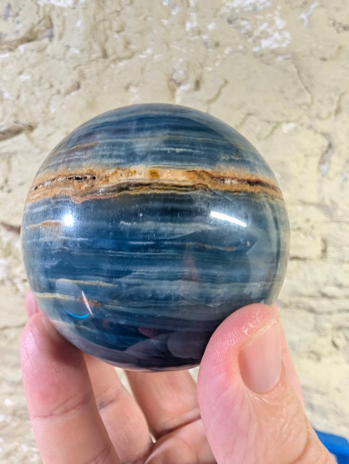 Side angle showing vivid banding and color zones in blue calcite sphere