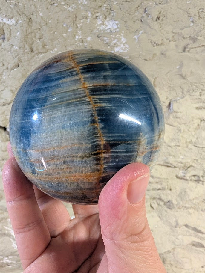 Blue calcite sphere with vertical brown iron seam detail