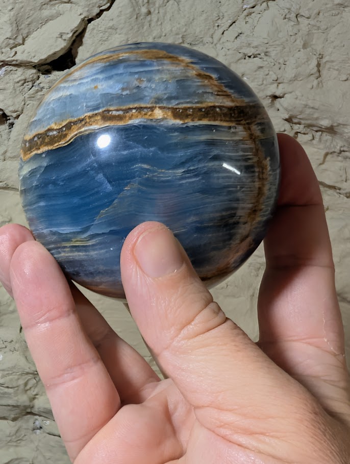 Blue onyx sphere showing vertical golden seam and polished banding