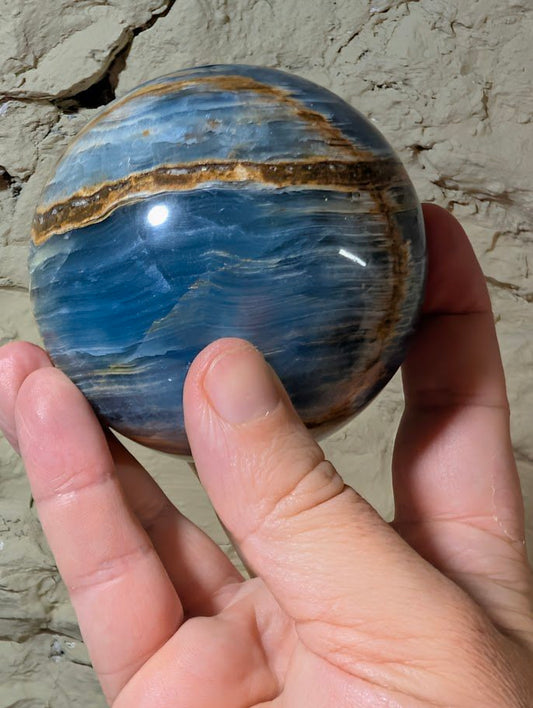 Blue onyx sphere showing vertical golden seam and polished banding
