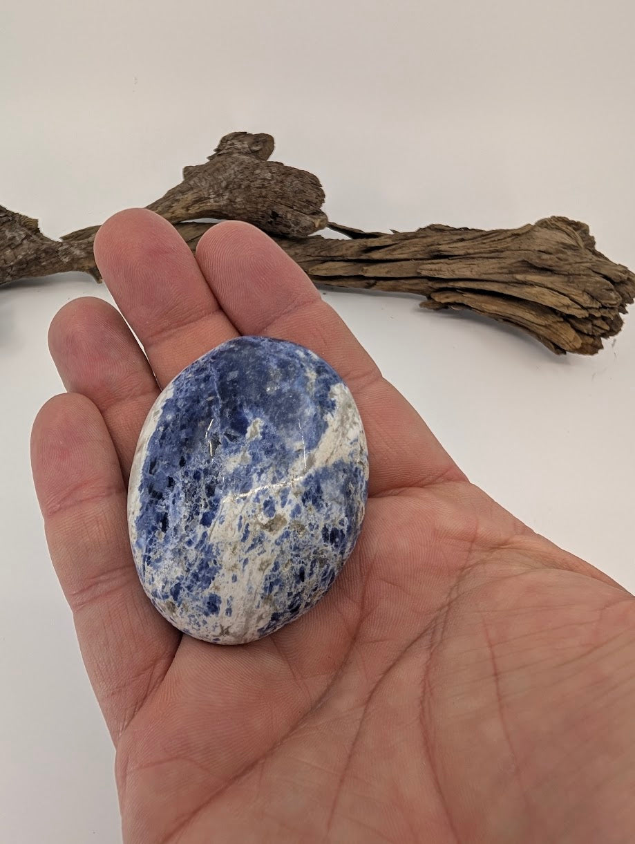 Large blue sodalite palm stone shown in hand for scale