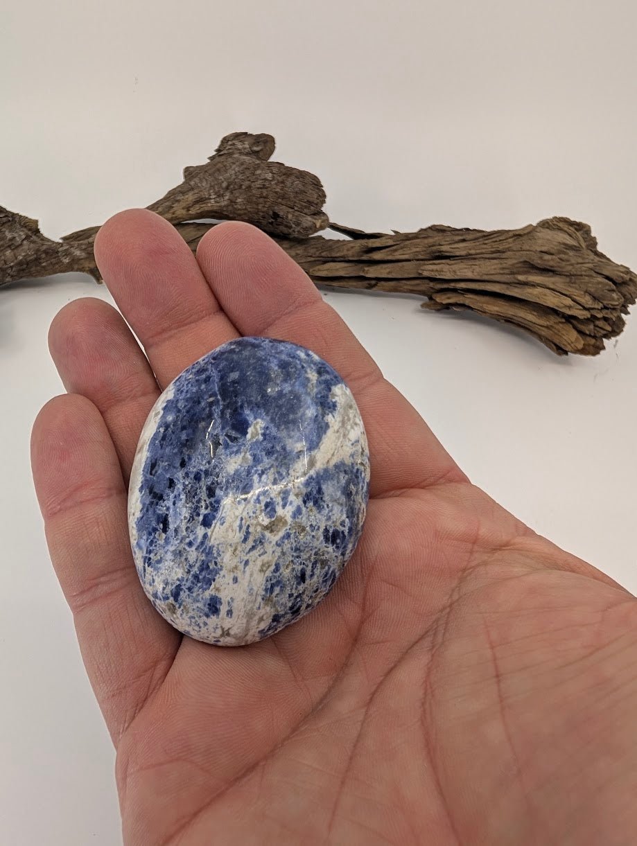 Large blue sodalite palm stone shown in hand for scale