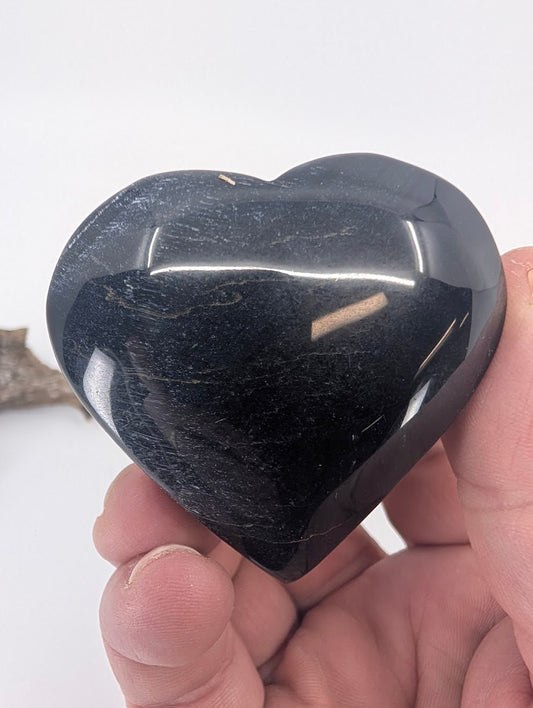 Hand holding a Blue Tiger Eye heart showing subtle blue shimmer.