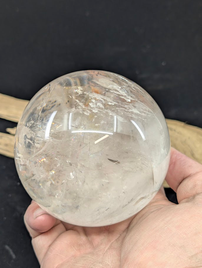 Macro photography detailing the fluid inclusion, trapped bubble, and surrounding golden hematite within a 1.12 kg Brazilian clear quartz sphere.