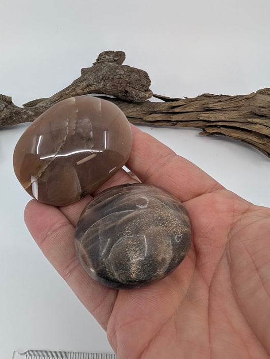 Brown moonstone palm stone shown in hand for scale