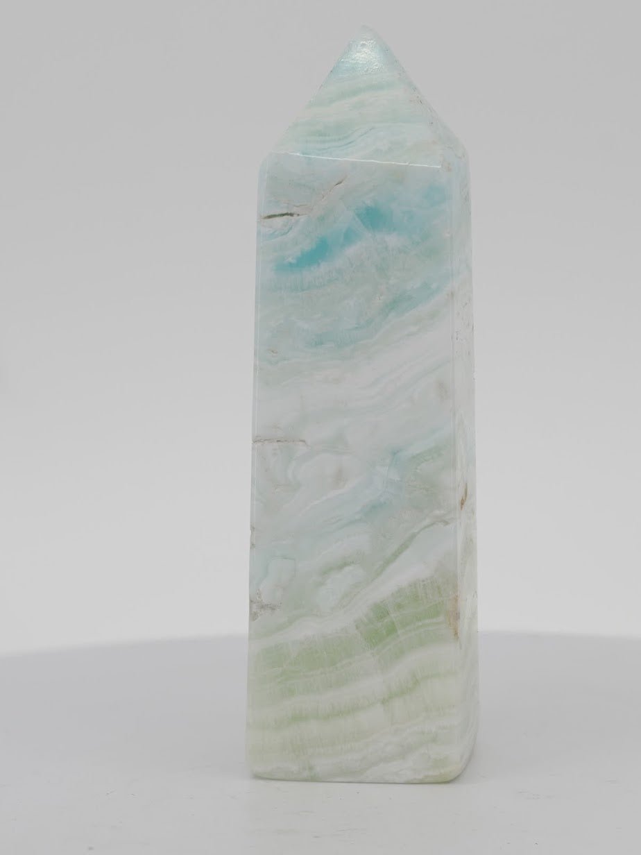Polished Caribbean Blue Calcite tower from Pakistan featuring translucent blue waves and white aragonite layers.