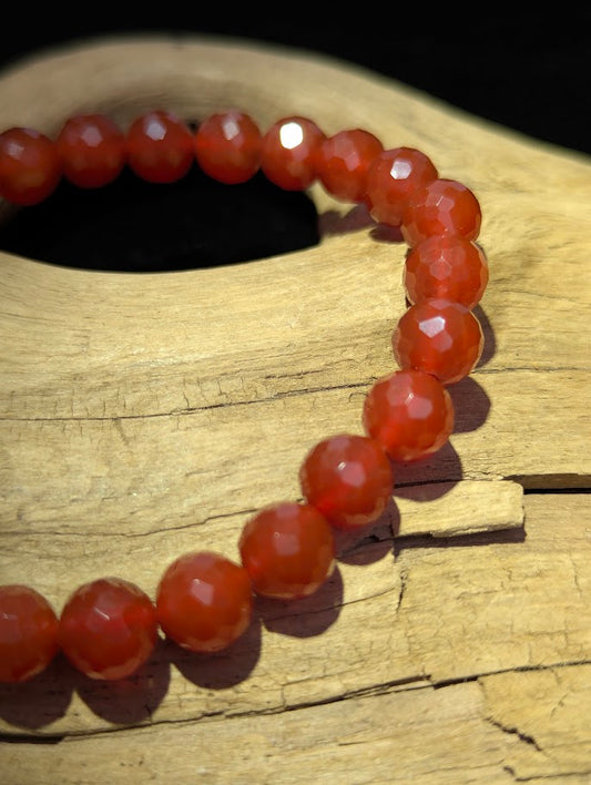 Macro close-up of 8mm faceted Carnelian beads highlighting the geometric cut and the deep, highly saturated red and orange chalcedony.