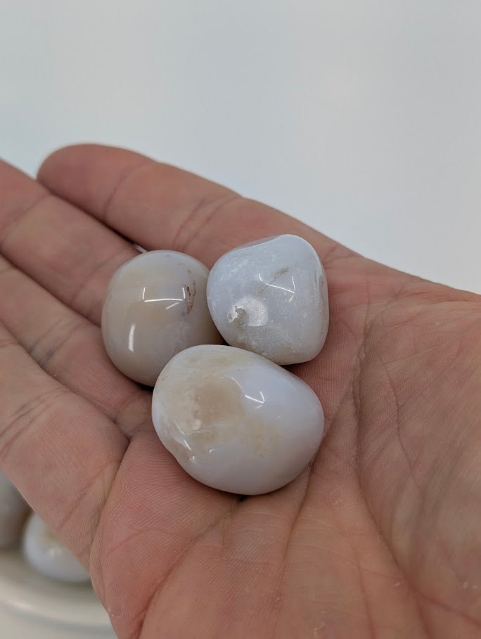 Chalcedony tumbled stones shown in hand for scale