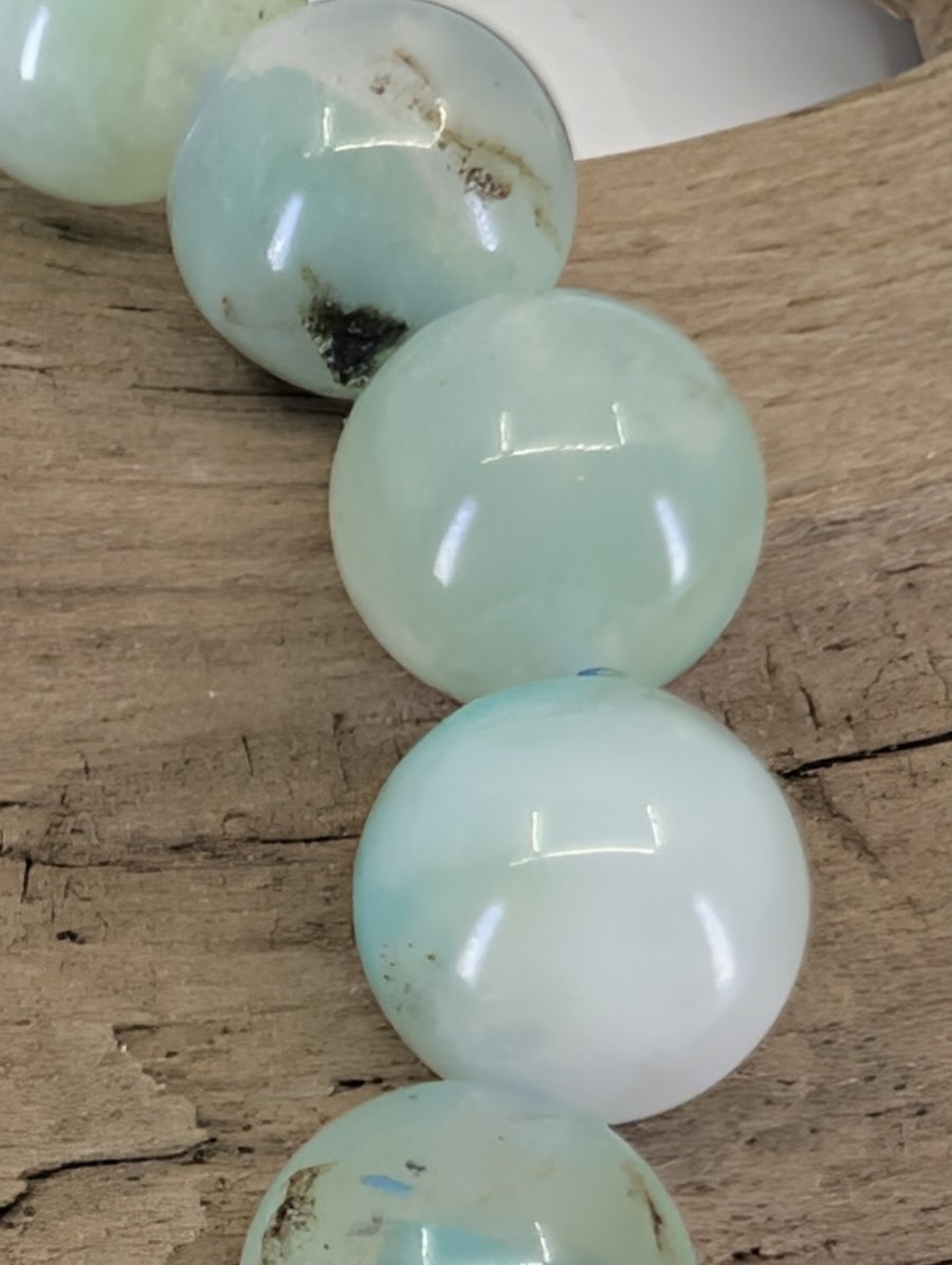 Macro view of Peruvian Chrysocolla beads showing high-gloss polish and authentic silica-rich mineral blooming.