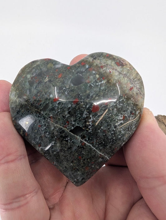 Hand holding a 100g Dragon Blood Jasper heart showing red veins.