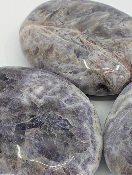 Close-up of Dream Amethyst Palm Stone highlighting natural chevron banding and quartz layers
