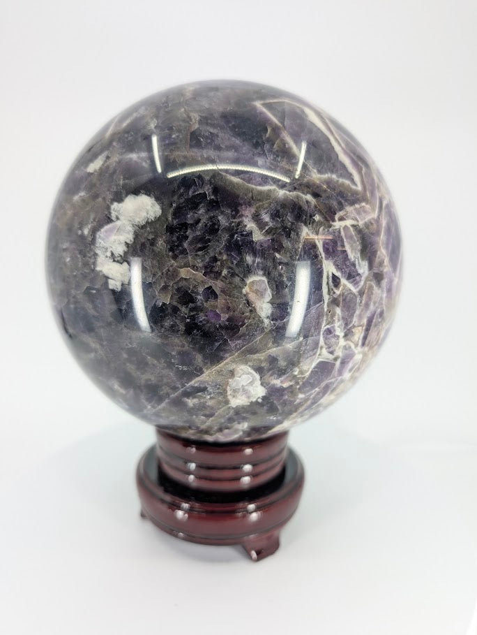 Angled close-up of Dream Amethyst sphere showing chevron pattern and translucence