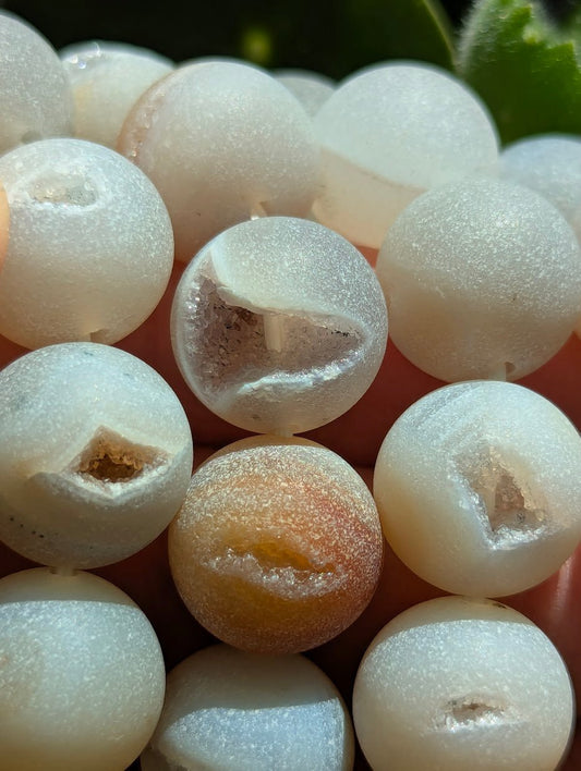 Macro detail of 14mm Agate beads highlighting the sparkling quartz crystals inside the natural vugs.