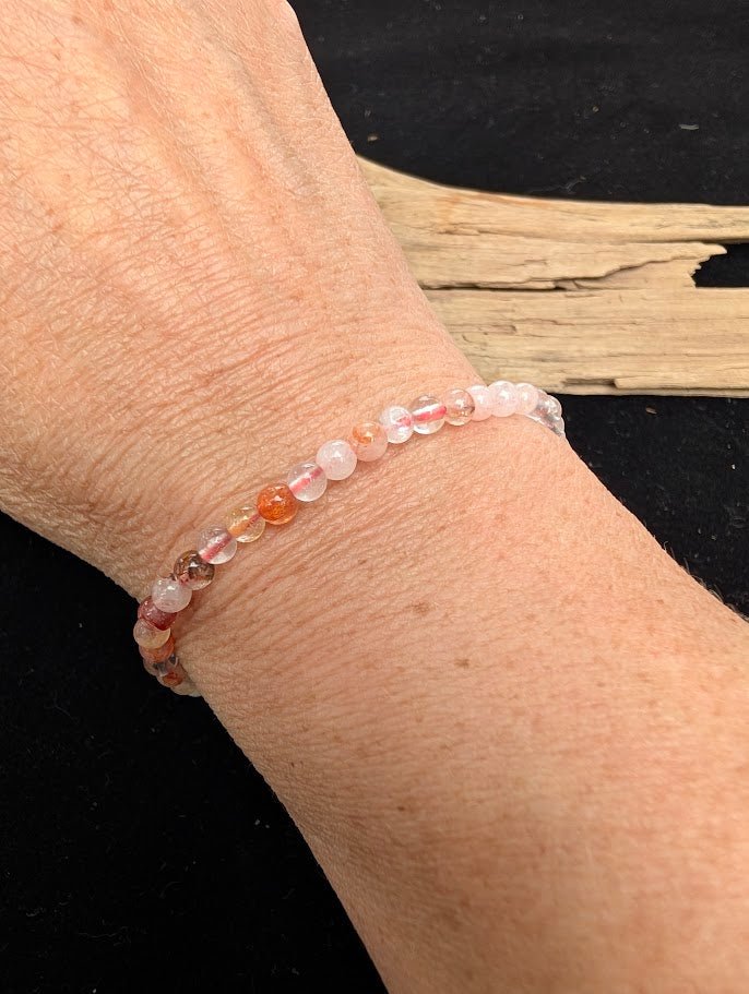 4mm polished Fire Quartz beaded stretch bracelet worn on a wrist for delicate size scale.