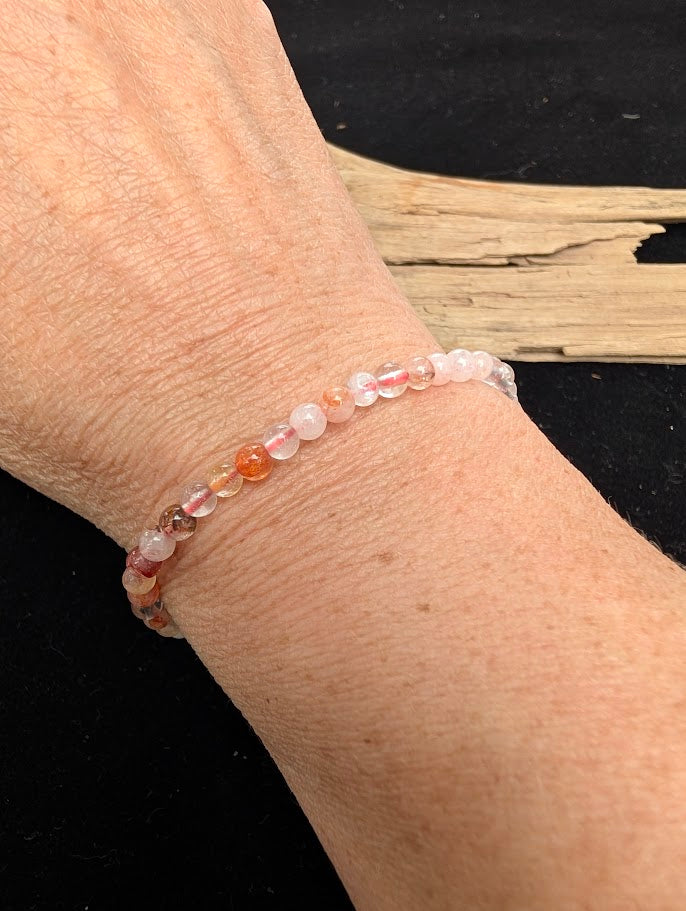 4mm polished Fire Quartz beaded stretch bracelet worn on a wrist for delicate size scale.