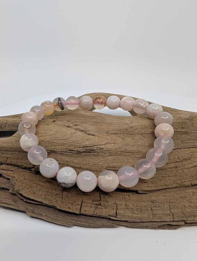 Flower Agate 8mm round bead stretch bracelet on driftwood showing blush-pink tones and white plume “flowers”