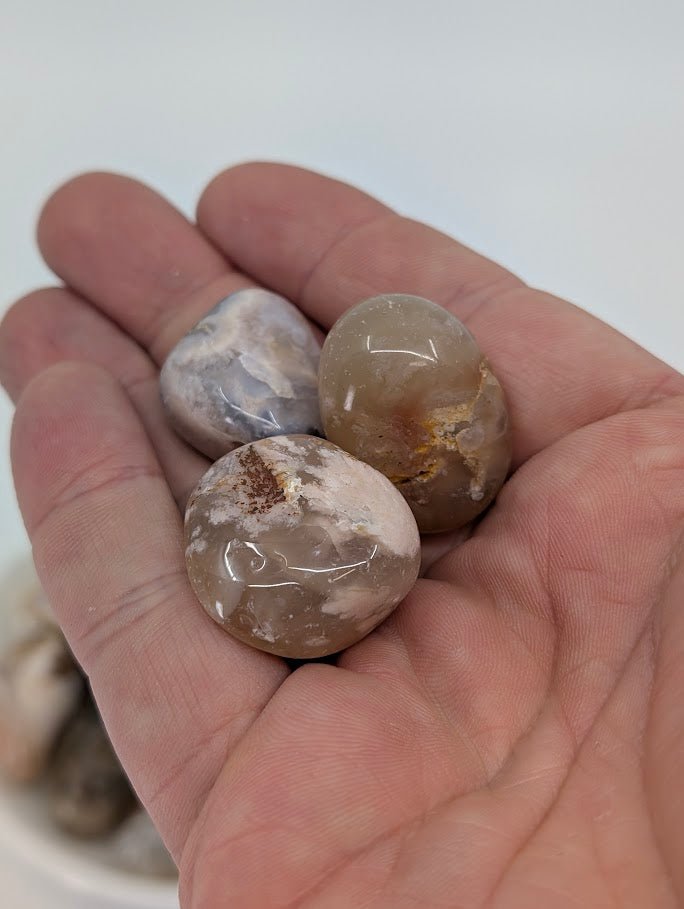 Flower Agate tumbled stones shown in hand for scale