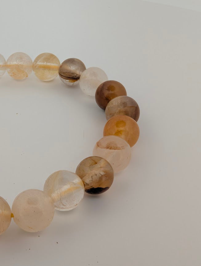 Angled close-up of Golden Healer Quartz 8mm beads with caramel and smoky accents