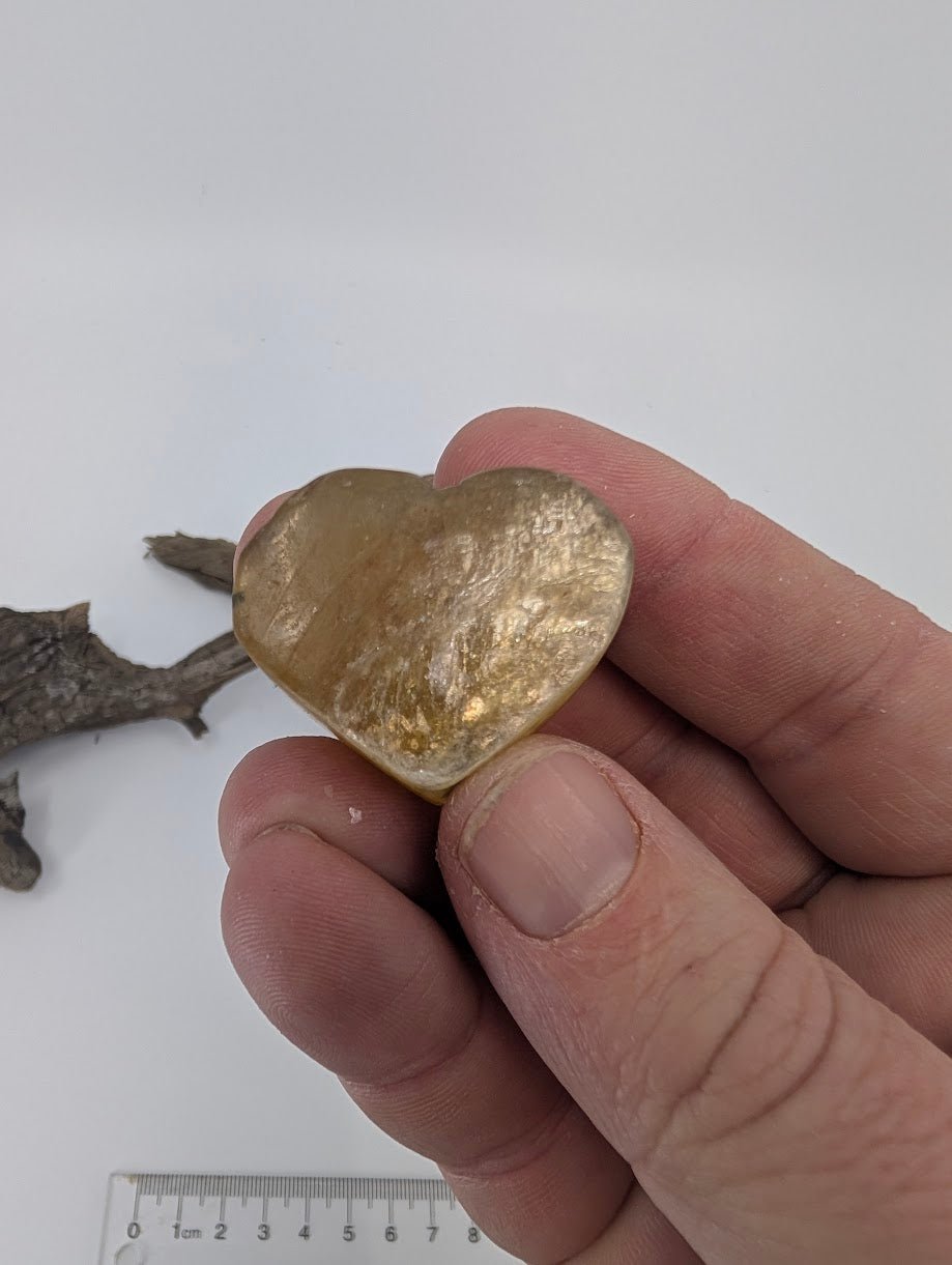 Fingers holding a tiny 20g Golden Mica heart showing translucency.