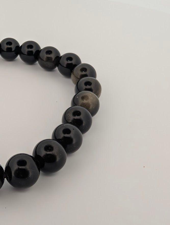 Angled shot of 6mm golden obsidian bracelet highlighting reflective chatoyance
