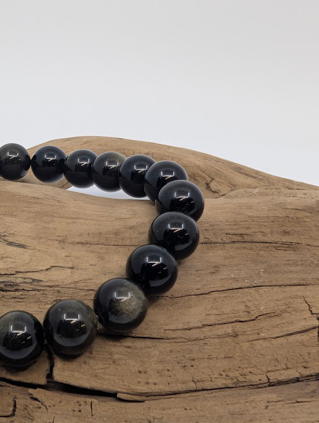 Macro of Golden Obsidian beads showing silky golden sheen on jet-black glass