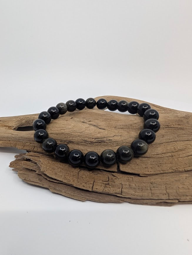 Golden Obsidian 8mm round bead stretch bracelet on driftwood with subtle golden sheen